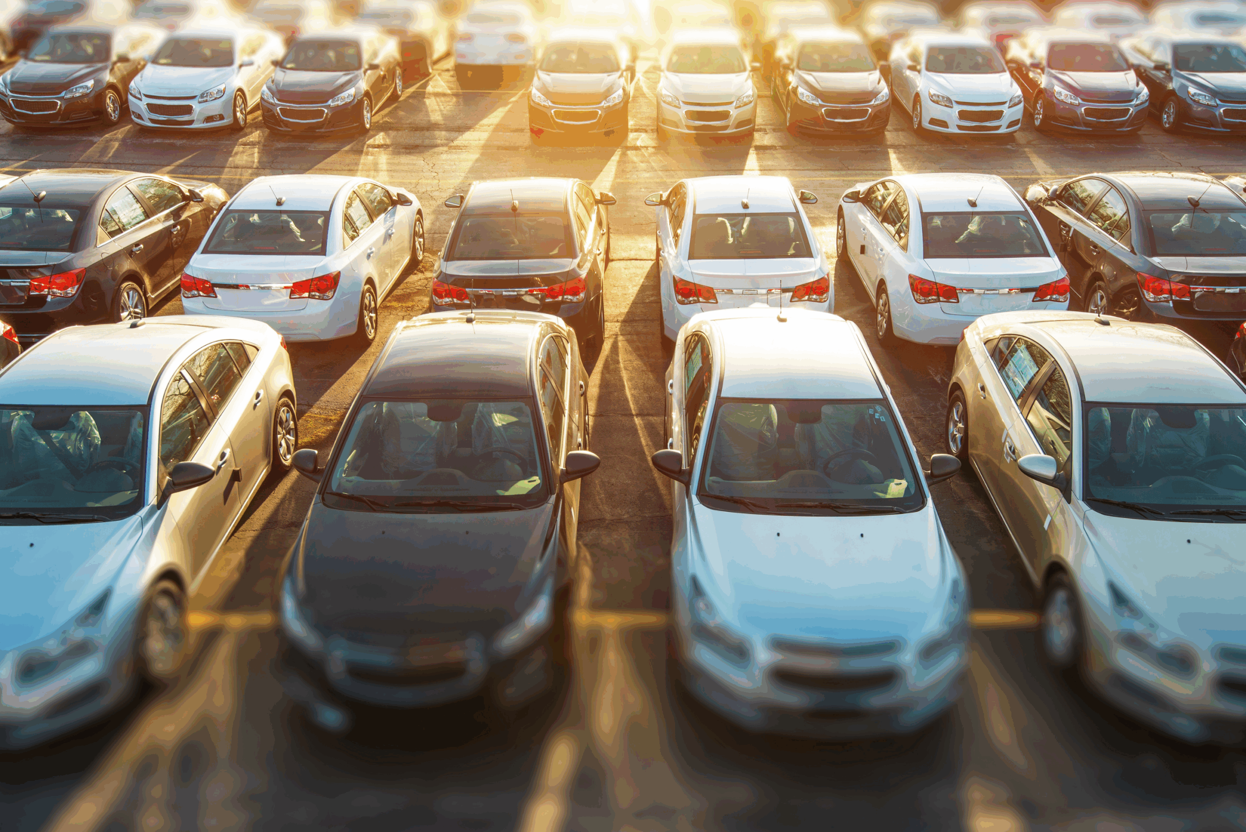 Multiple cars lined up closely together in a large open parking area.