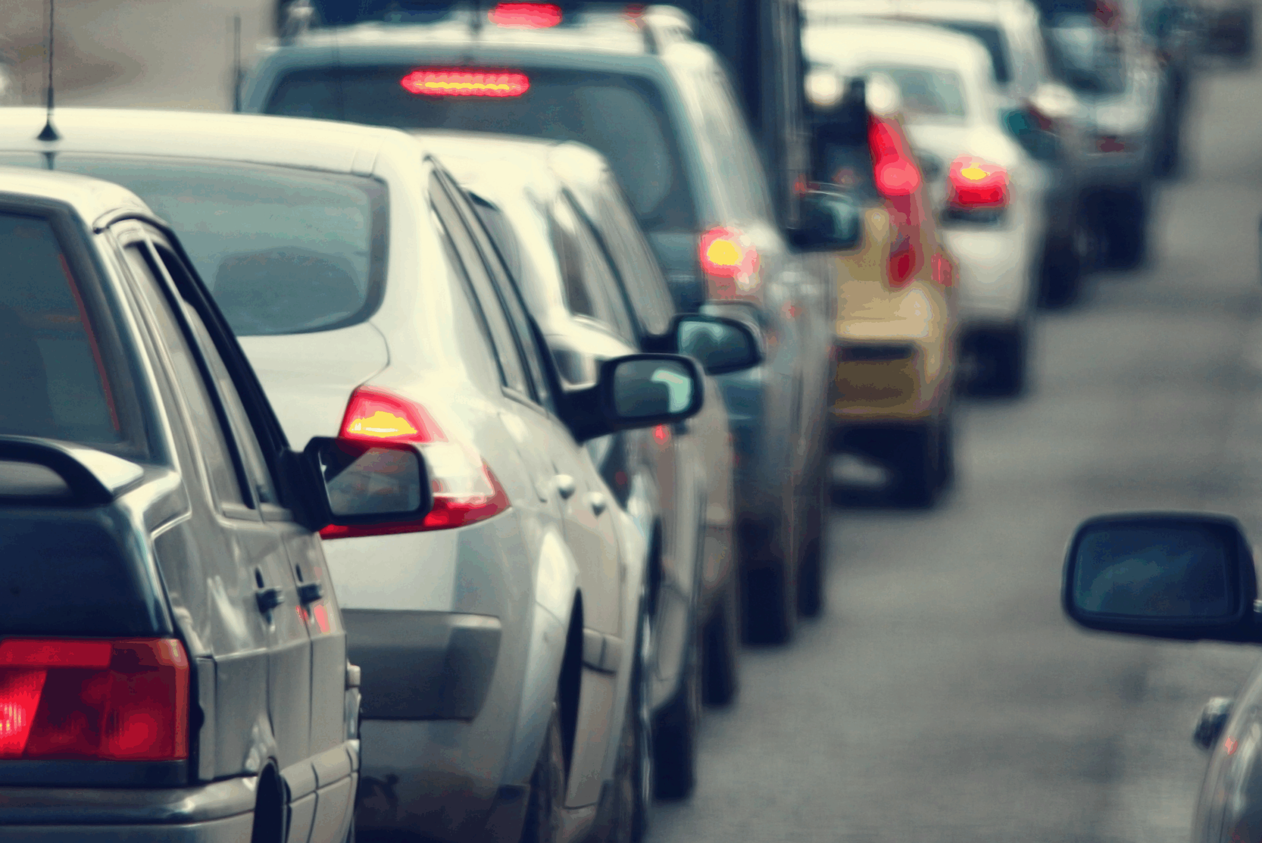 Cars lined up closely on a busy city street during heavy traffic.